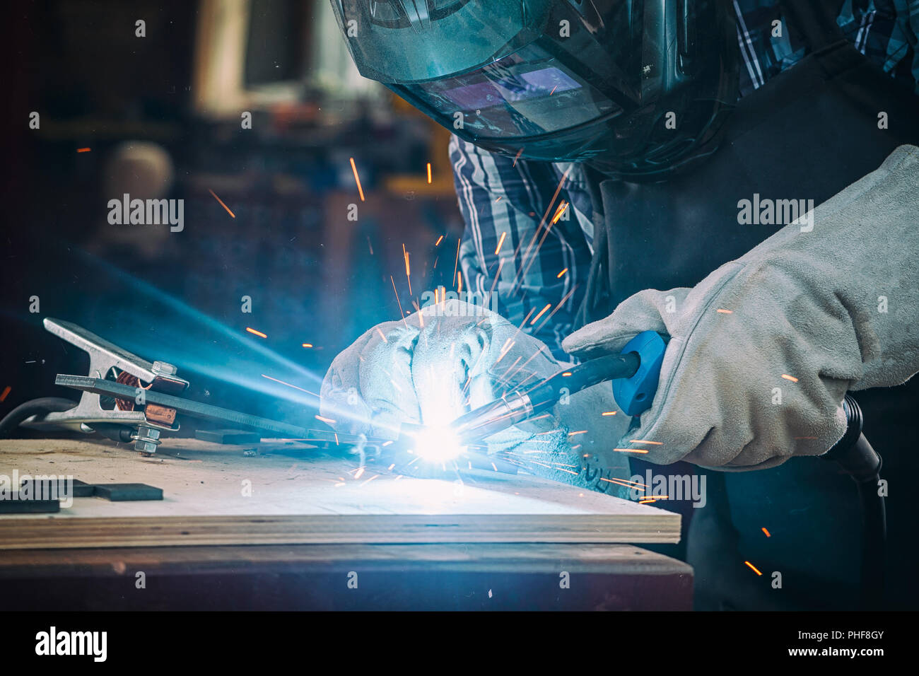 Starke mann Schweißer in Arbeitskleidung bemüht und Schweißnähte mit einem Schweißgerät Metall in der Werkstatt Stockfoto