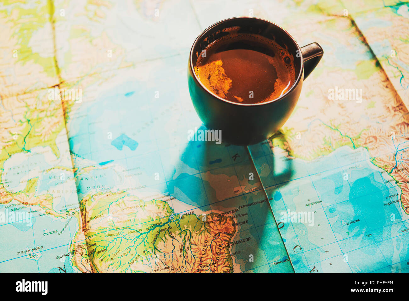 Frische Tasse Kaffee mit Weltkarte im Hintergrund; konzeptionelle Bild von Reise Reise Hobeln mit Weltkarte; Reisen Hintergrund Stockfoto