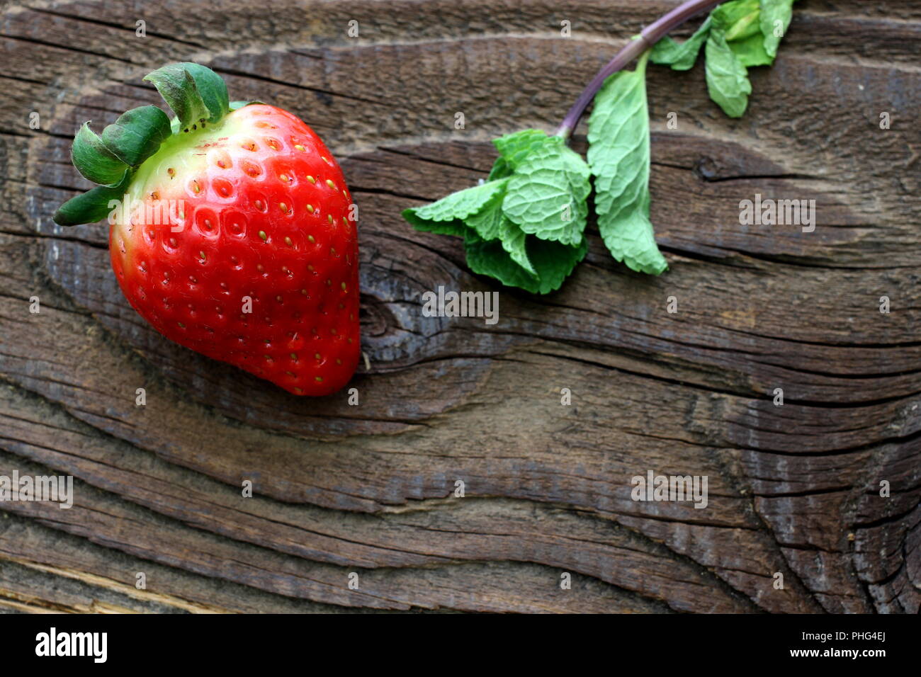 Single reife Erdbeere und Minze auf Antike, rustikale Tabelle Stockfoto