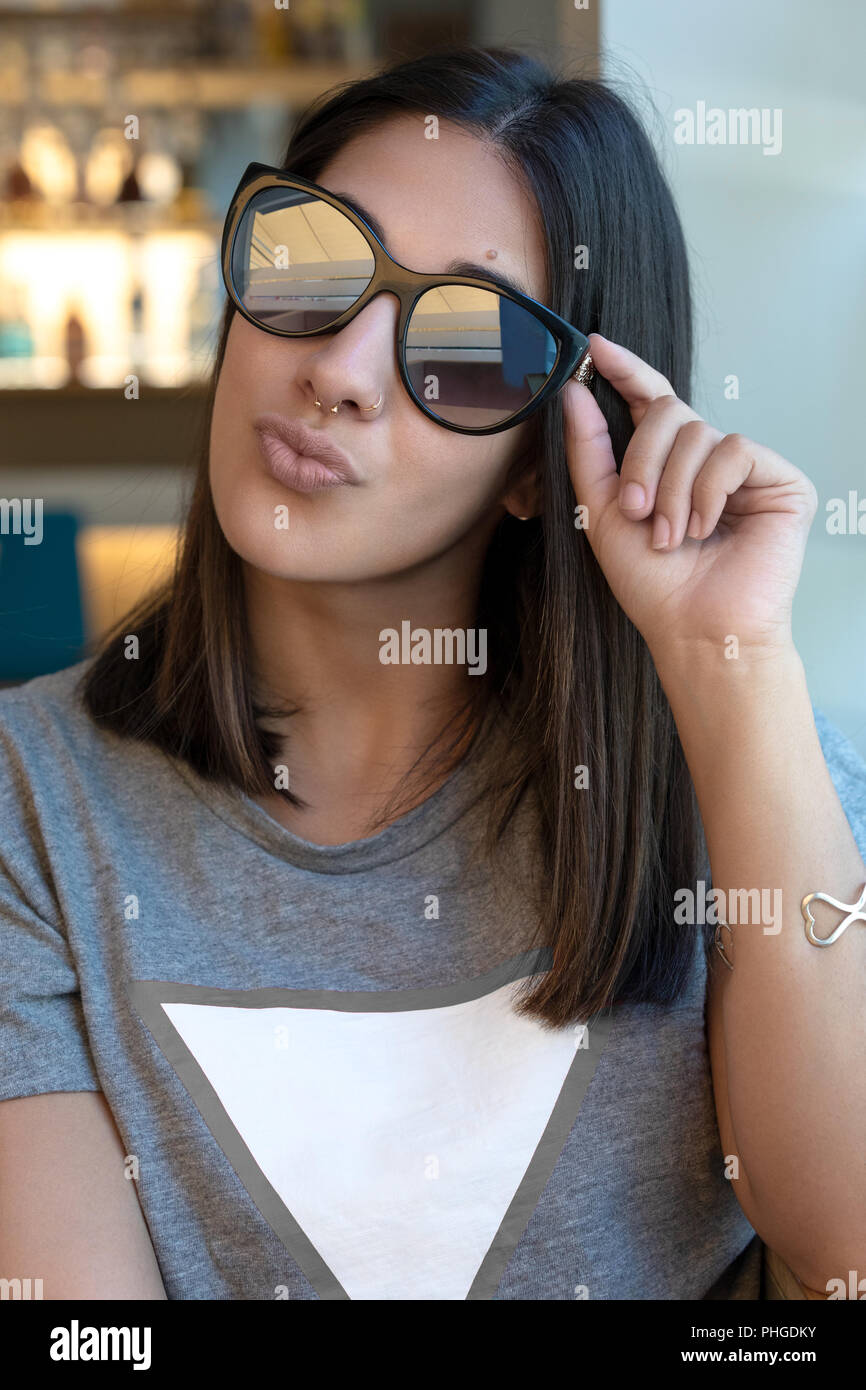 Pretty girl Holding ihre Sonnenbrille und küssen die Luft in einem bar Stockfoto