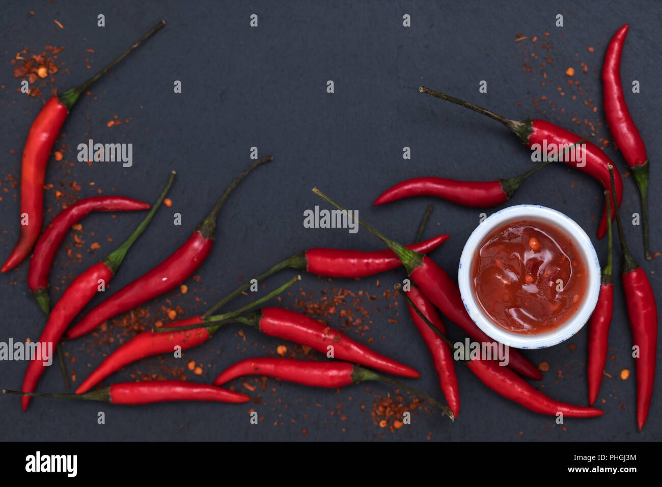 Hot Chili Sauce Paste mit frischen und rissig Pfeffer auf schwarzem Schiefer Hintergrund der Ansicht von oben Stockfoto