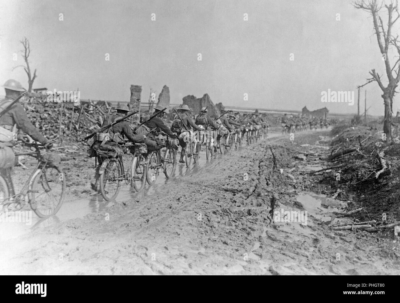 Ersten Weltkrieg 1914-1918. Britische Soldaten mit ihren Fahrrädern sind zu Fuß auf einer schlammigen Straße irgendwo in Frankreich. Sie sind vorbei abgerissen Gebäude und Ruinen. Stockfoto