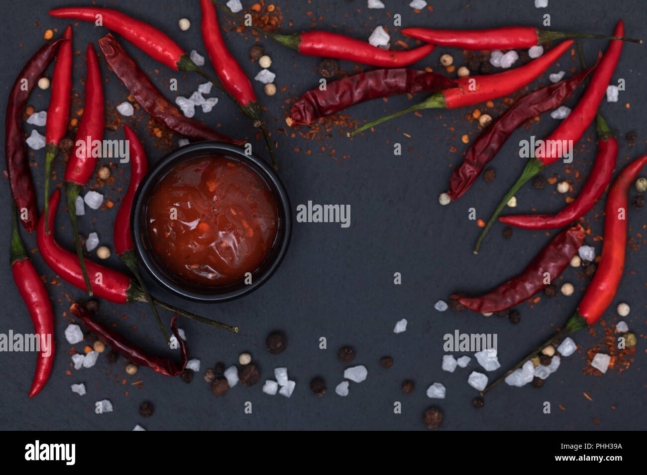Hot Chili Sauce Paste mit frischen und rissig Pfeffer auf schwarzem Schiefer Hintergrund der Ansicht von oben Stockfoto