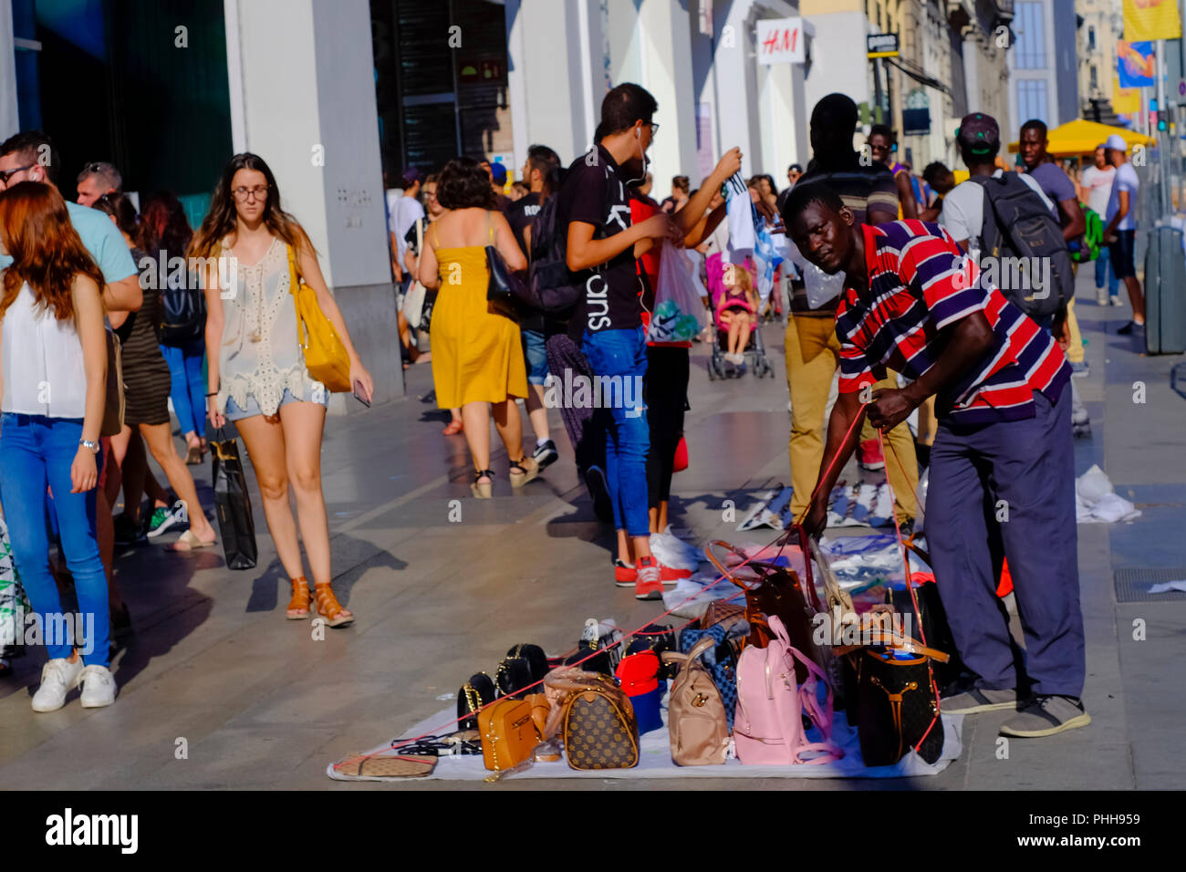 Eine Straße hawker "Top Manta ' Verkauf von gefälschten Handtaschen in Gran Via voller Menschen. Stockfoto