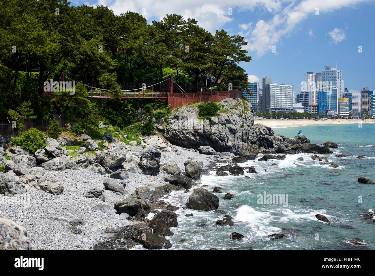 Haeundae Bay, Busan, Korea. Zerklüftete Küste mit kleinen Bucht und Fußgängerweg und Brücke in Dongbaek Park Stockfoto