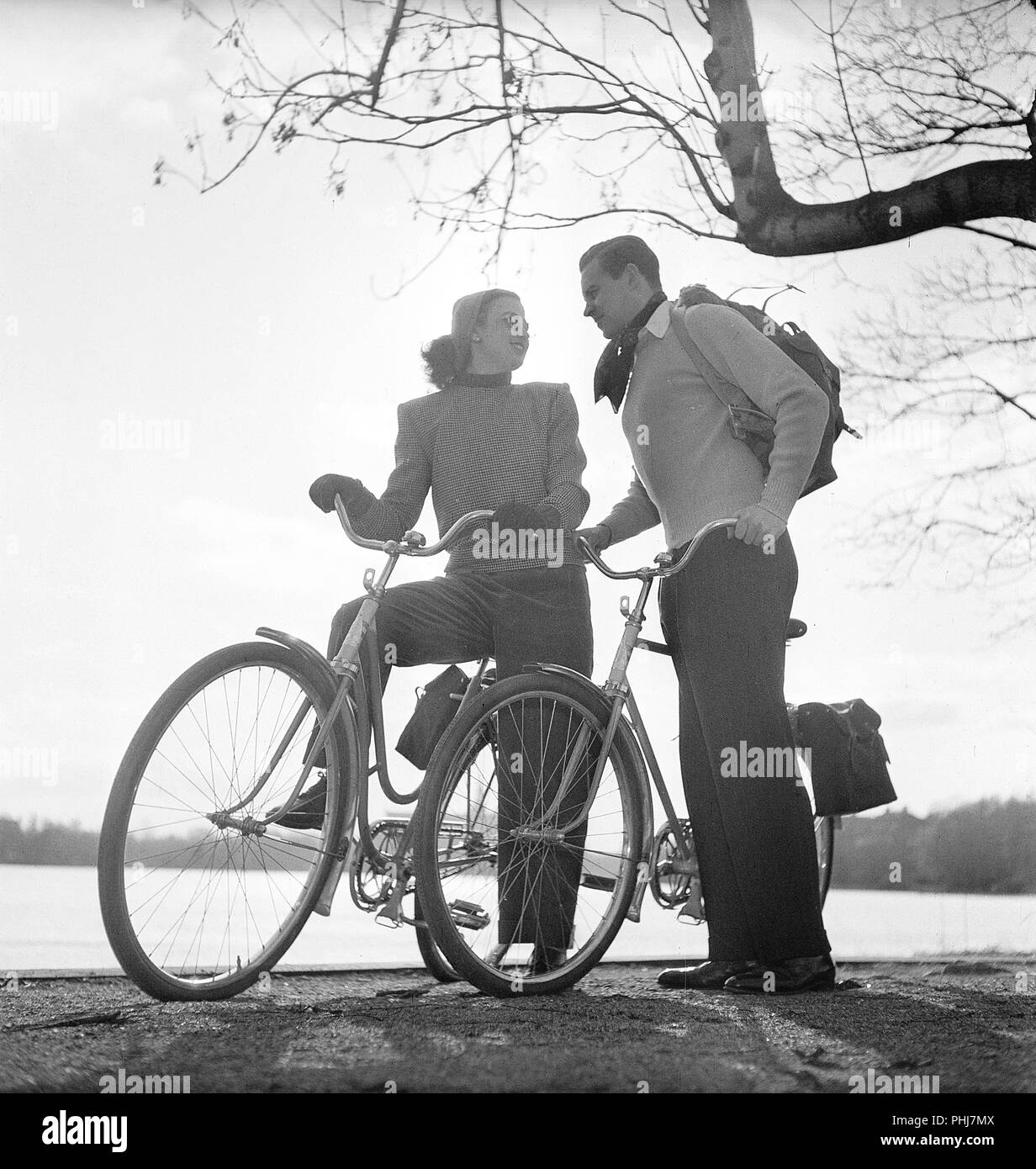 1940 s Paar auf Fahrrädern. Ein junges Paar ist auf einer Tour mit dem Fahrrad an einem sonnigen Frühlingstag. Sie haben praktische Taschen in den Regalen der Fahrräder, wo Sie das Essen bei einem Picknick transportieren kann. Schweden 1947. Foto Kristoffersson AB 11-10 Stockfoto
