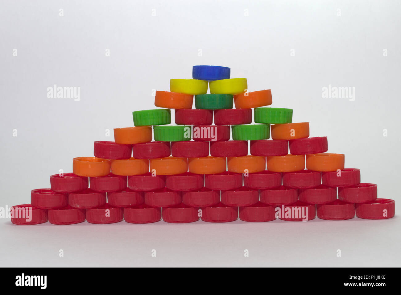 Flache Pyramiden aus farbigem Kunststoff Flaschenverschlüsse auf grauem Hintergrund Stockfoto