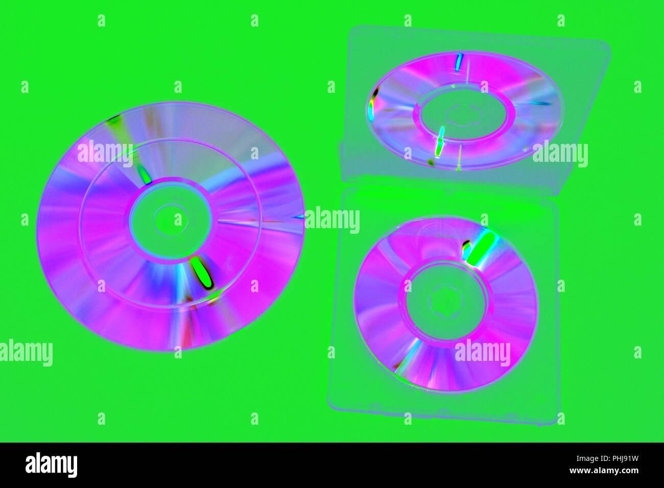 Bild in Komplementärfarben Töne: Doppelseitige Kunststoffbox für Mini-CDs, geöffnet. irisierenden Compact Discs auf grünem Hintergrund. Mit clipping Pass Stockfoto