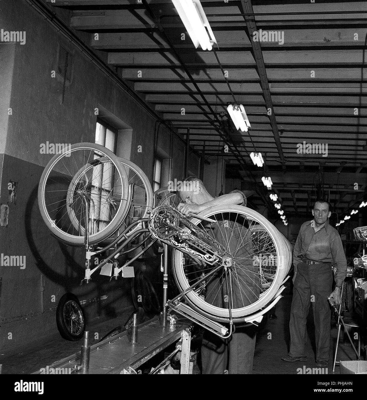 Fahrradfabrik in den 1950er Jahren. Ein Arbeiter am Fahrrad Hersteller Nymans in Uppsala arbeitet an der Produktionslinie mit Frauen Fahrräder. Schweden 1956 ref CV 15-9 Stockfoto