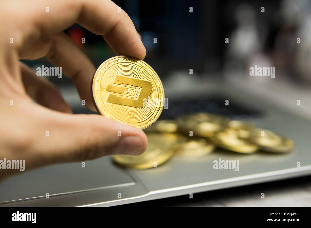 Männliche Geschäftsmann Hand strich Münze auf dem Hintergrund der Laptop Tastatur und Stapel von Goldmünzen. Virtuelles Geld und finanzielle Wachstum Konzept. Handel Bergbau von Dash Coin Stockfoto