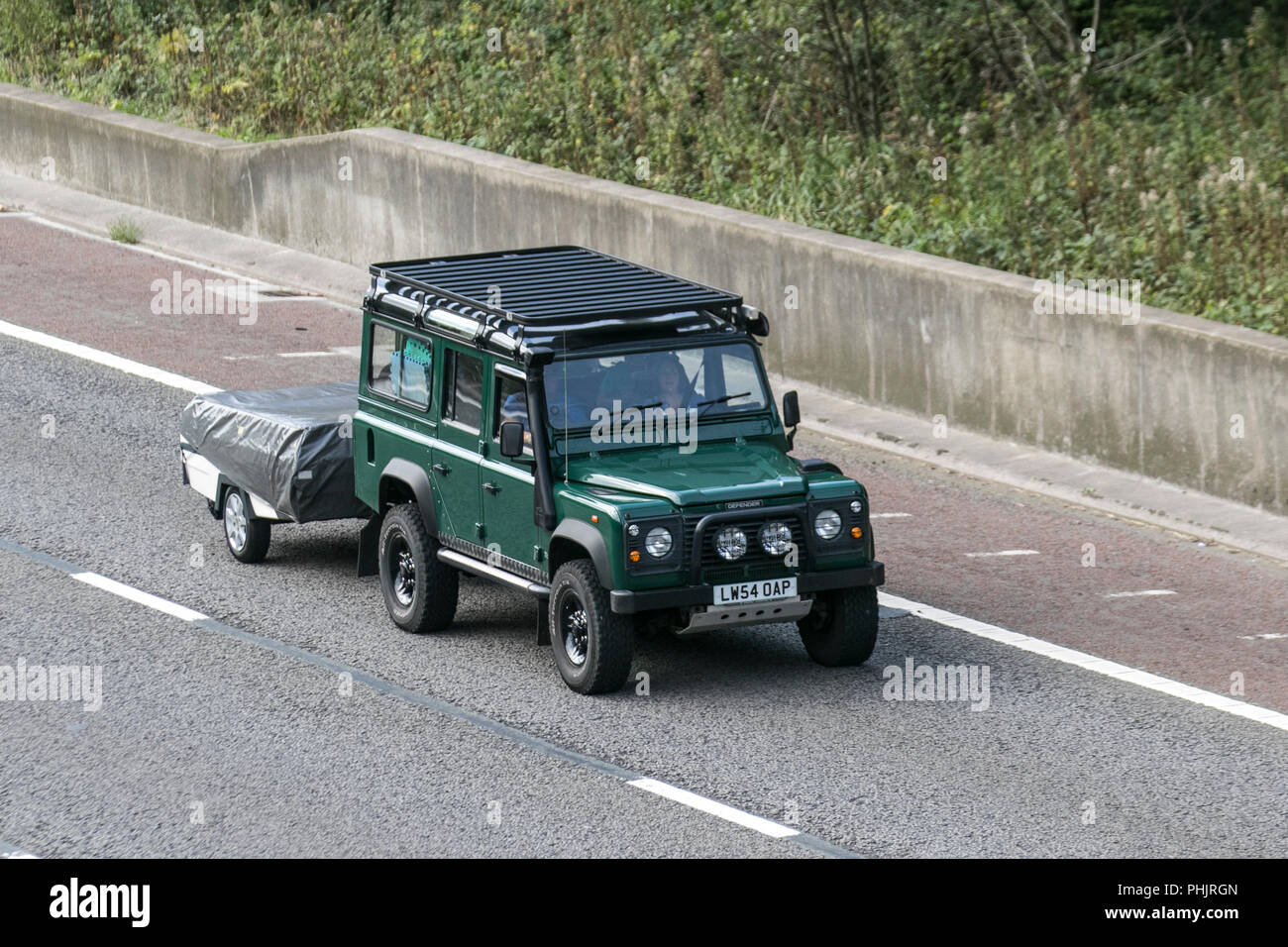 2005 (54) Land Rover Defender 110 County TD5 mit Schnorchelauspuff, Freizeit, Geländeeinsatz, robustes Fahrzeug, mit Anhänger auf der Autobahn M6, Großbritannien Stockfoto