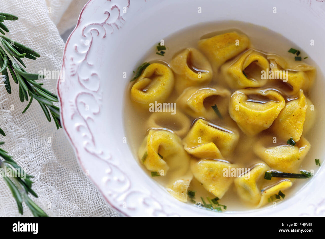 Suppe mit Tortellini in einer weißen Schüssel. Stockfoto