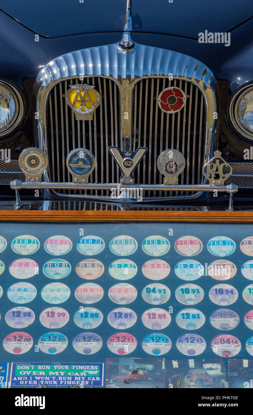 Den Frontgrill eines klassischen oder colectors Auto mit einer Reihe von altmodischen Steuer Discs oder road fund Lizenzen in einem Rahmen. Stockfoto