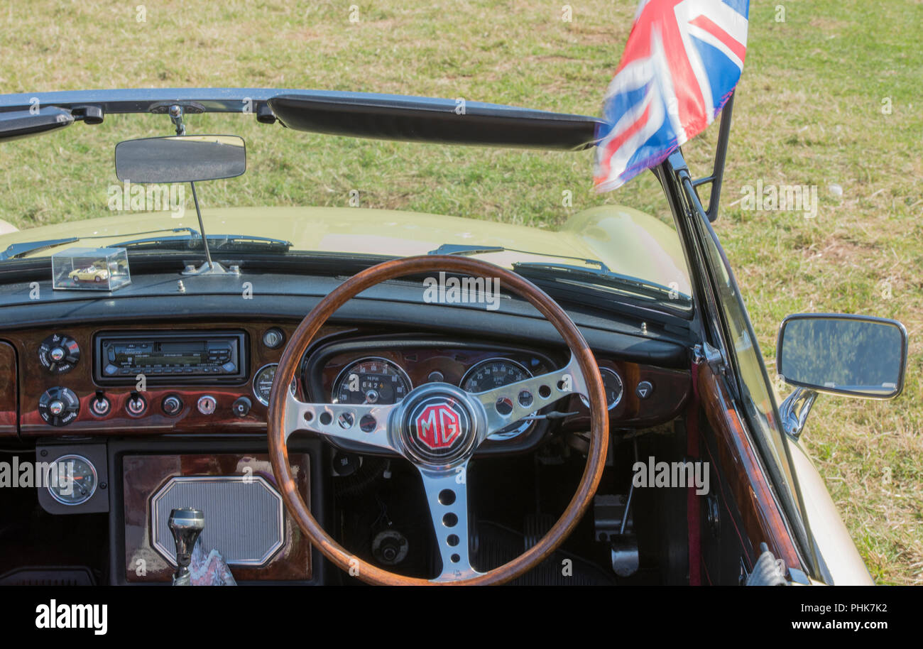 Eine britische mg Sportwagen, die die Union Flag oder Jack von der Frontscheibe. Vintage MG Midget ot MGB GT-Sportwagen Engländer Dashboard in Nussbaum. Stockfoto