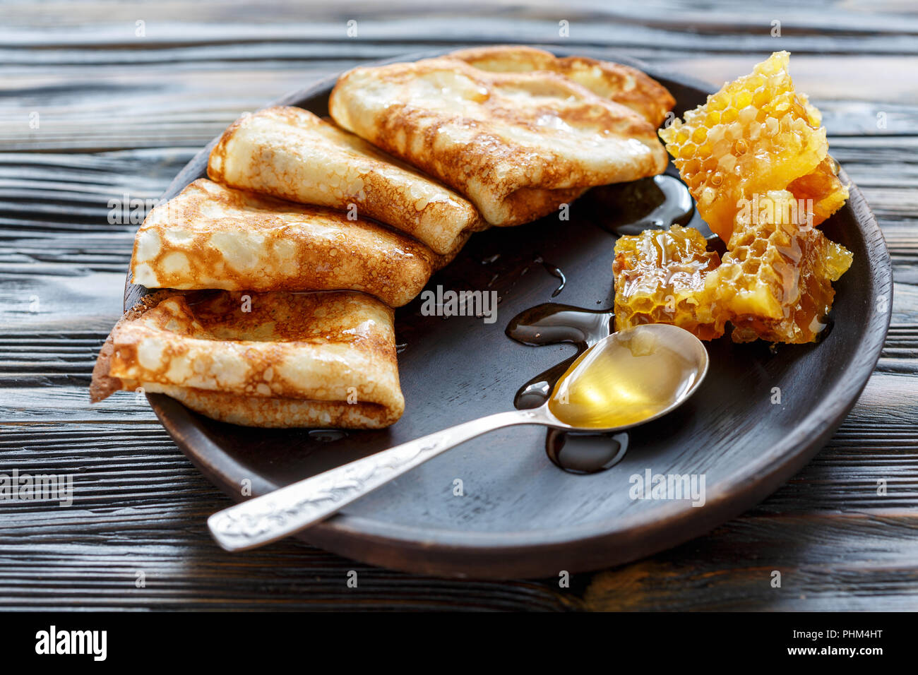 Pfannkuchen mit Honig auf einer Holzplatte. Stockfoto