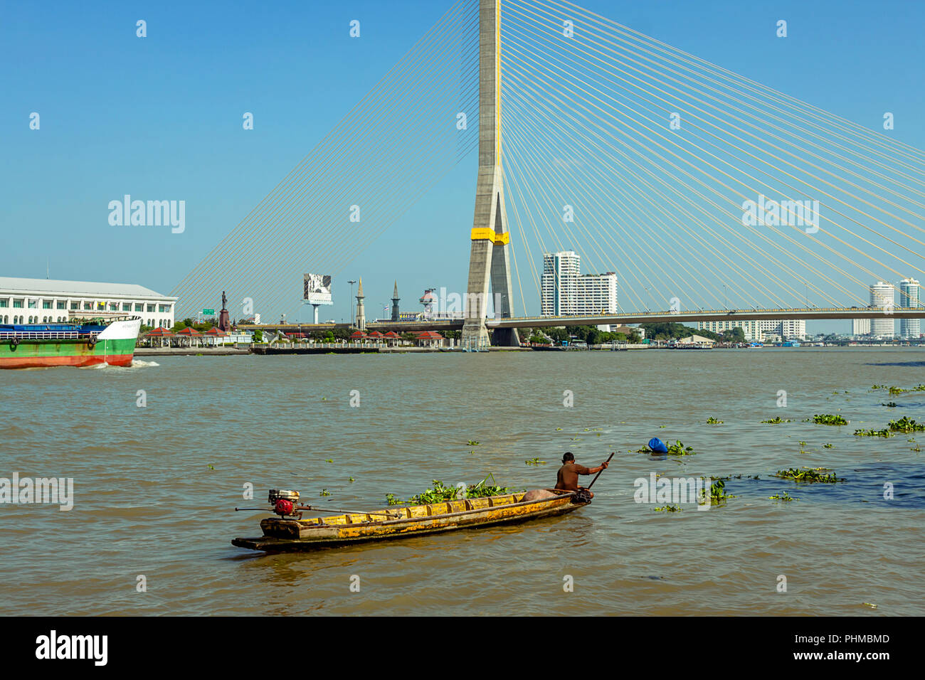 Lokales Boot mit einer Person Rudern in einem Boot in der Nähe der grossen Brücke Span auf dem Chao Praya Fluss in Bangkok. Stockfoto