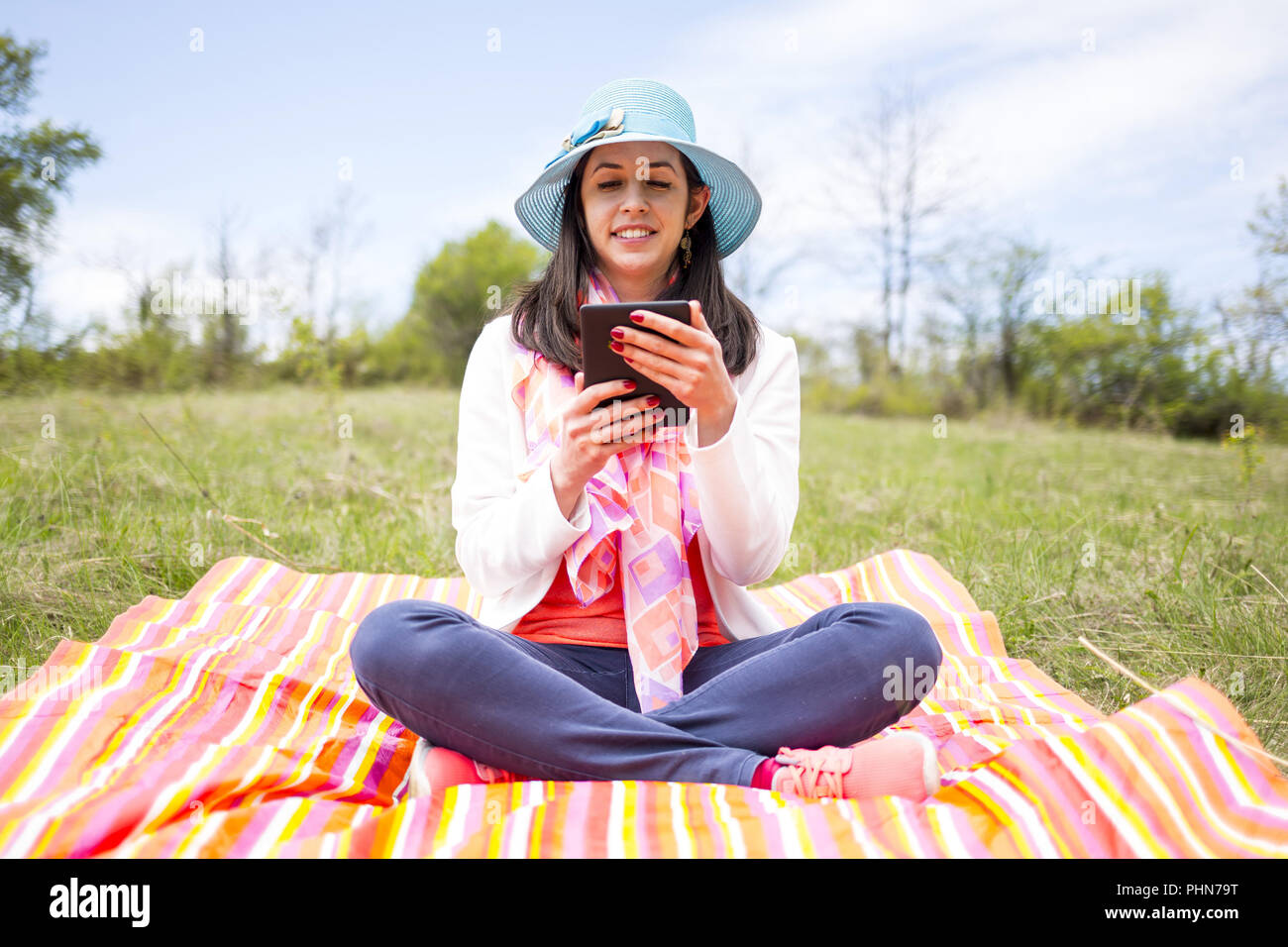 Attraktive lächelnde junge Frau mit e-book/Tablette Stockfoto
