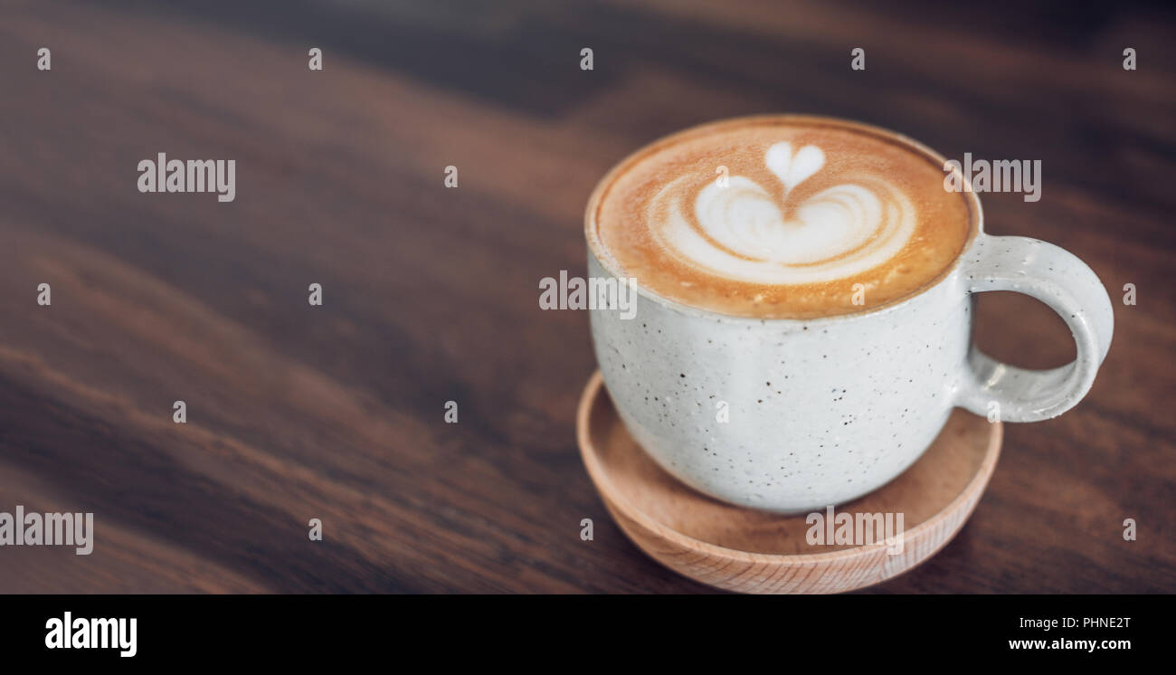 Heißen Cappuccino Tasse auf Holz- Fach mit latte Kunst auf Holz Tisch im Cafe. Essen und Trinken Konzept. Kopieren sie Raum lassen für das Hinzufügen von Text Stockfoto