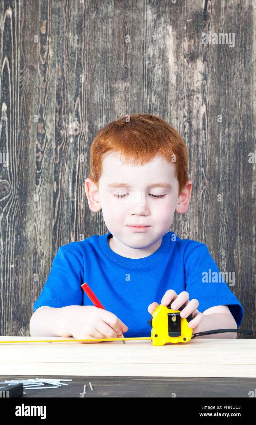 Schöne rothaarige Junge mit Baumaschinen Kennzeichnung Board für den Bau Stockfoto