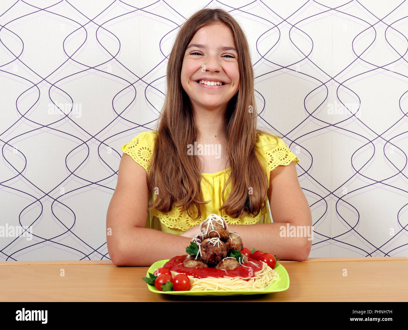 Glückliches Mädchen mit Spaghetti und Frikadellen für Mittagessen Stockfoto