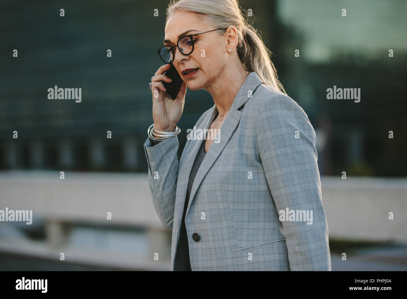Portrait von Senior kaukasische Frau Gespräch am Handy in der Stadt. Frauen im Business Suit walking im freien Gespräch am Handy. Stockfoto