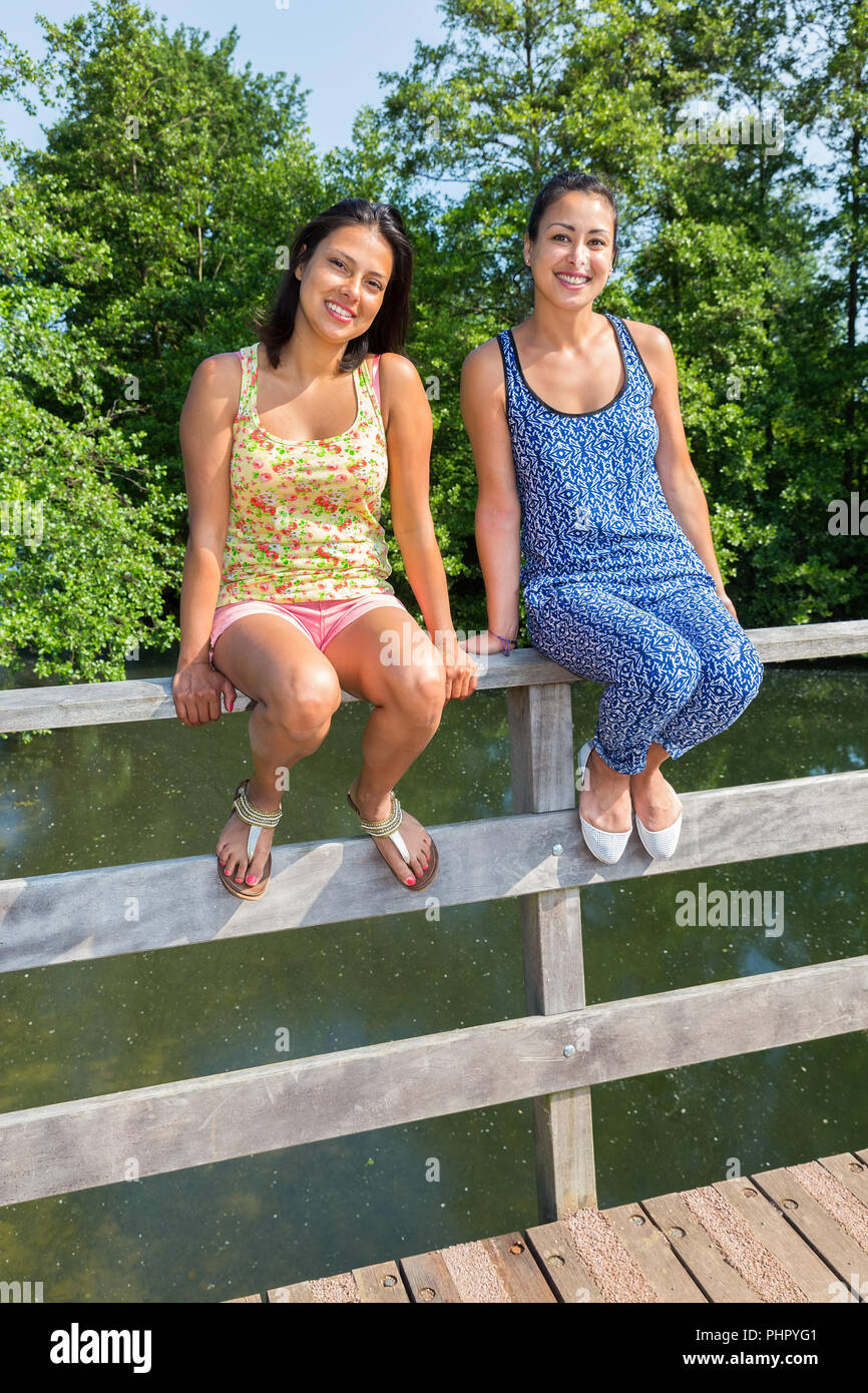 Zwei Frauen sitzen zusammen auf der Brücke Geländer Stockfoto