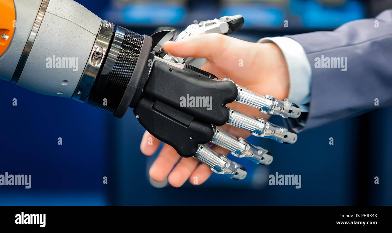 Hand eines Geschäftsmannes Händeschütteln mit einem Droiden Roboter. Das Konzept der menschlichen Interaktion mit der künstlichen Intelligenz. Stockfoto