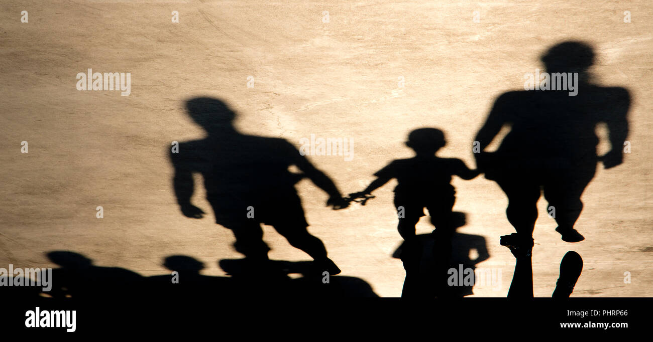 Schatten Silhouette von Mutter, Vater und Sohn, das Hände beim Gehen in Richtung auf misty Sommer Straße und viele Leute hinter Ihnen, in sepia schwarz und wh Stockfoto