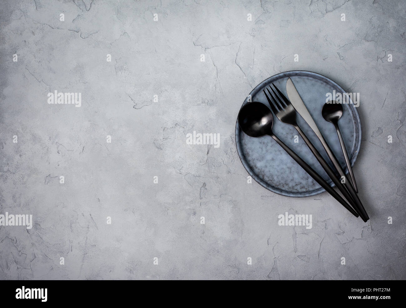 Leeren Teller, Gabel, Löffel und Messer auf einem grauen konkreten Hintergrund. Ansicht von oben Stockfoto