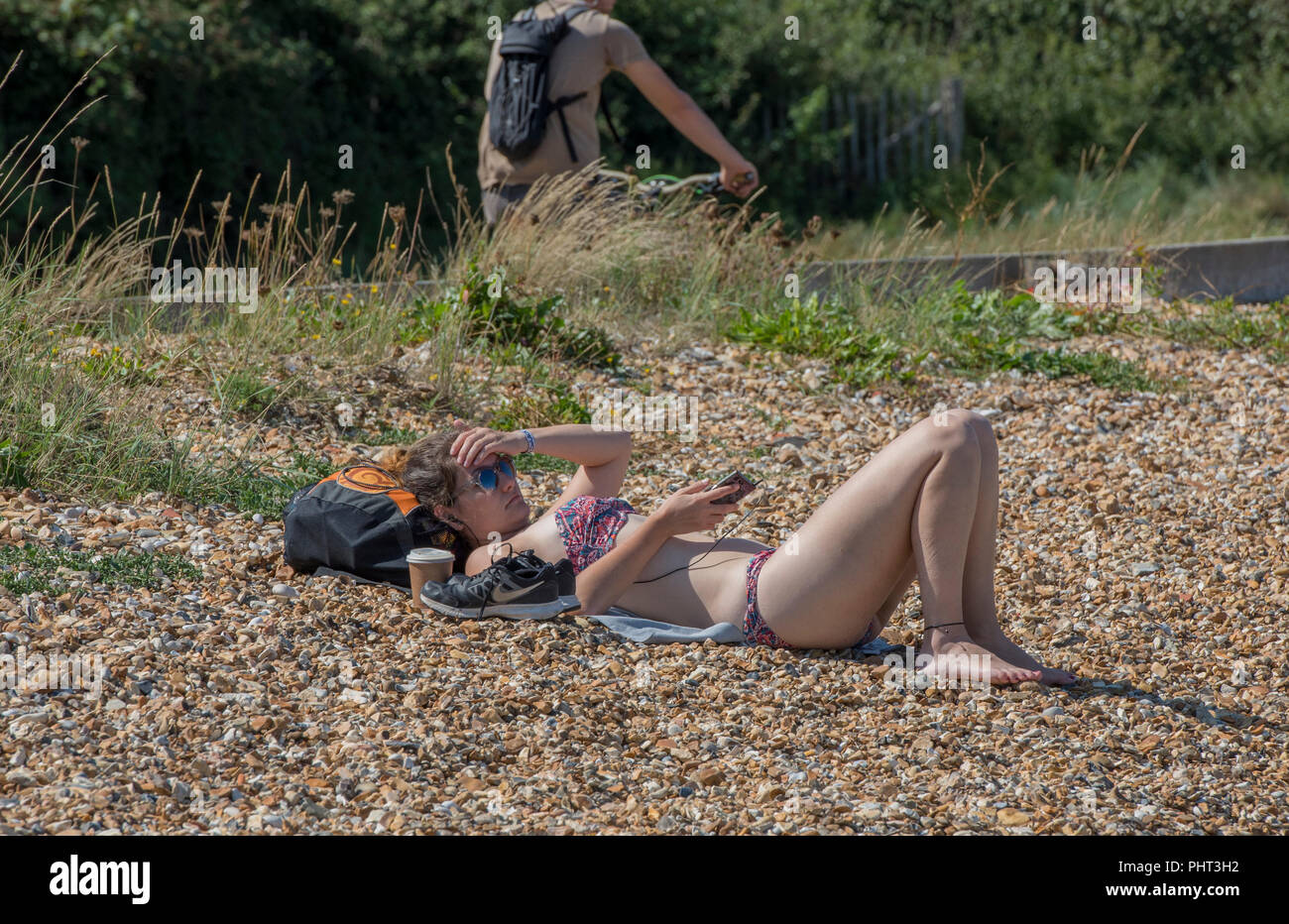 Eine attraktive junge Frau trägt einen Bikini oder Badeanzug Sonnenbad oder Solarium auf der Isle of Wight Strand in der Sommerhitze und Sonnenschein. Stockfoto