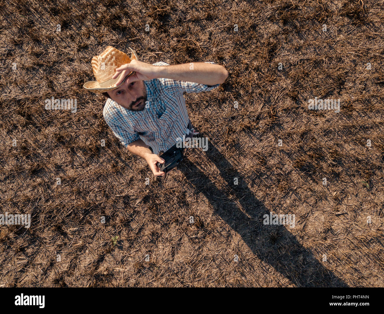 Blick von oben auf die männlichen Bauern fliegen eine Drohne mit Fernbedienung in der Getreideernte Stroh Feld im Sommer Sonnenuntergang Stockfoto