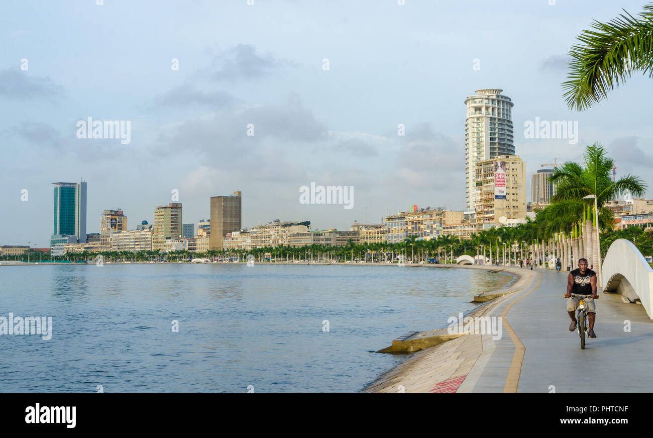 Luanda, Angola - 28. April 2014: Bucht von Luanda mit Strandpromenade und Mann auf dem Fahrrad auf bewölkten Tag. Stockfoto