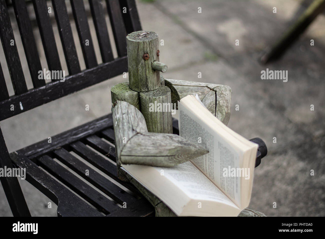 Holzfigur saß auf einem Garten Stuhl außerhalb ein Buch lesen Stockfoto