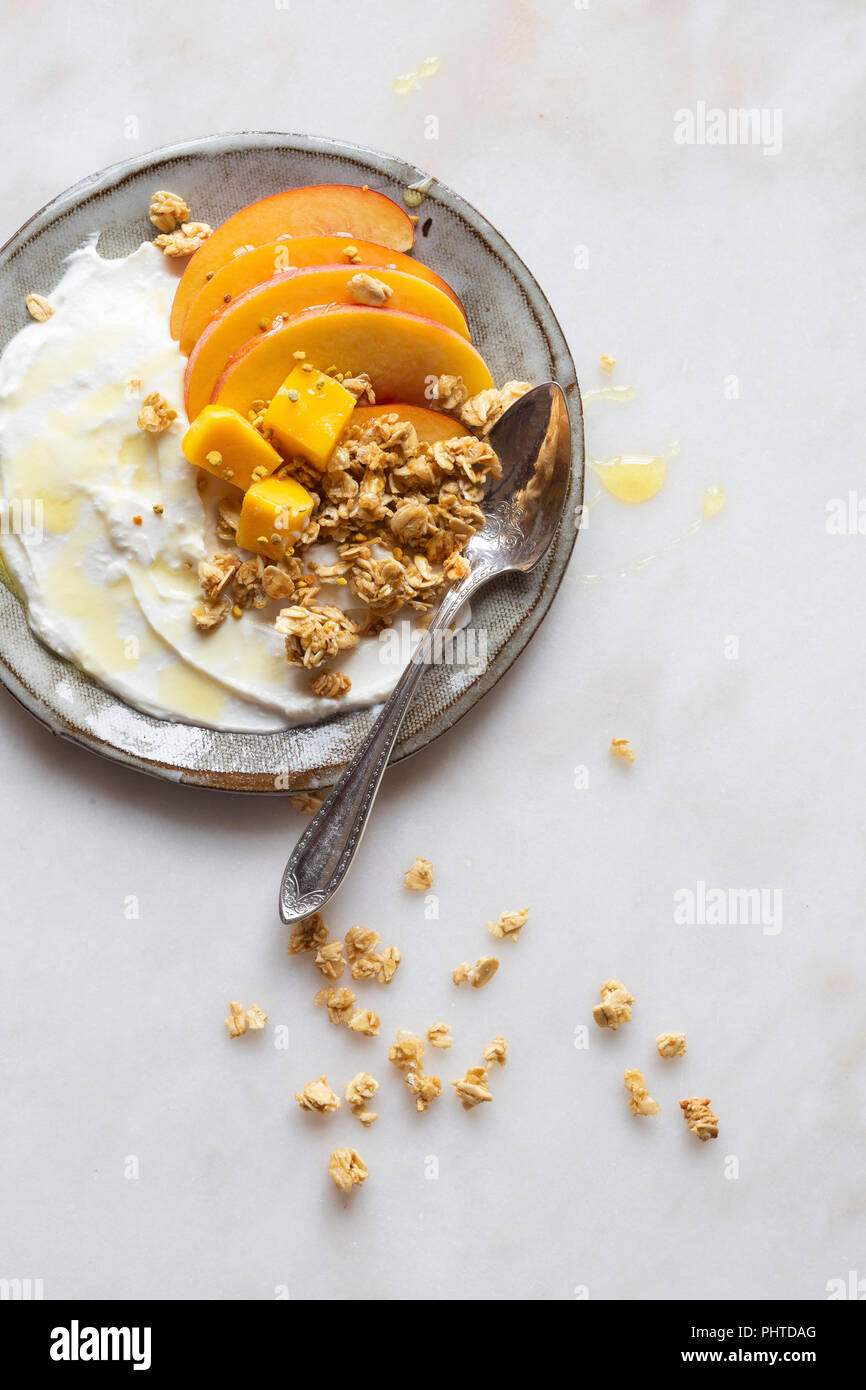 Glutenfreies Frühstück zu gehen - griechischer Joghurt, Pfirsich, Mango und Müsli mit Honig und Blütenpollen. Stockfoto