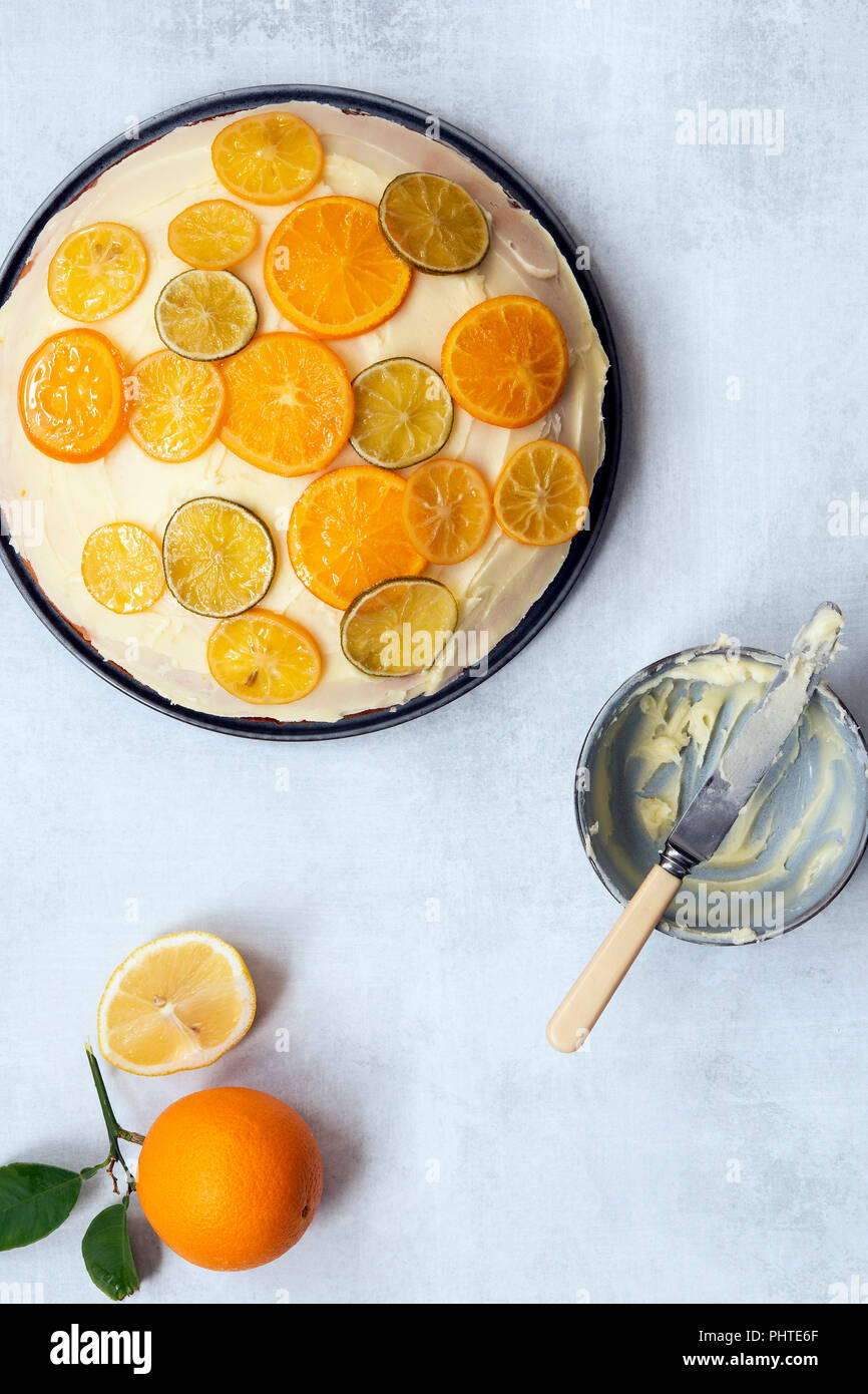 Eine Runde orange Kuchen mit Butter und Puderzucker mit Scheiben von kandierte Zitrone, Limette und orange gehalten. Stockfoto