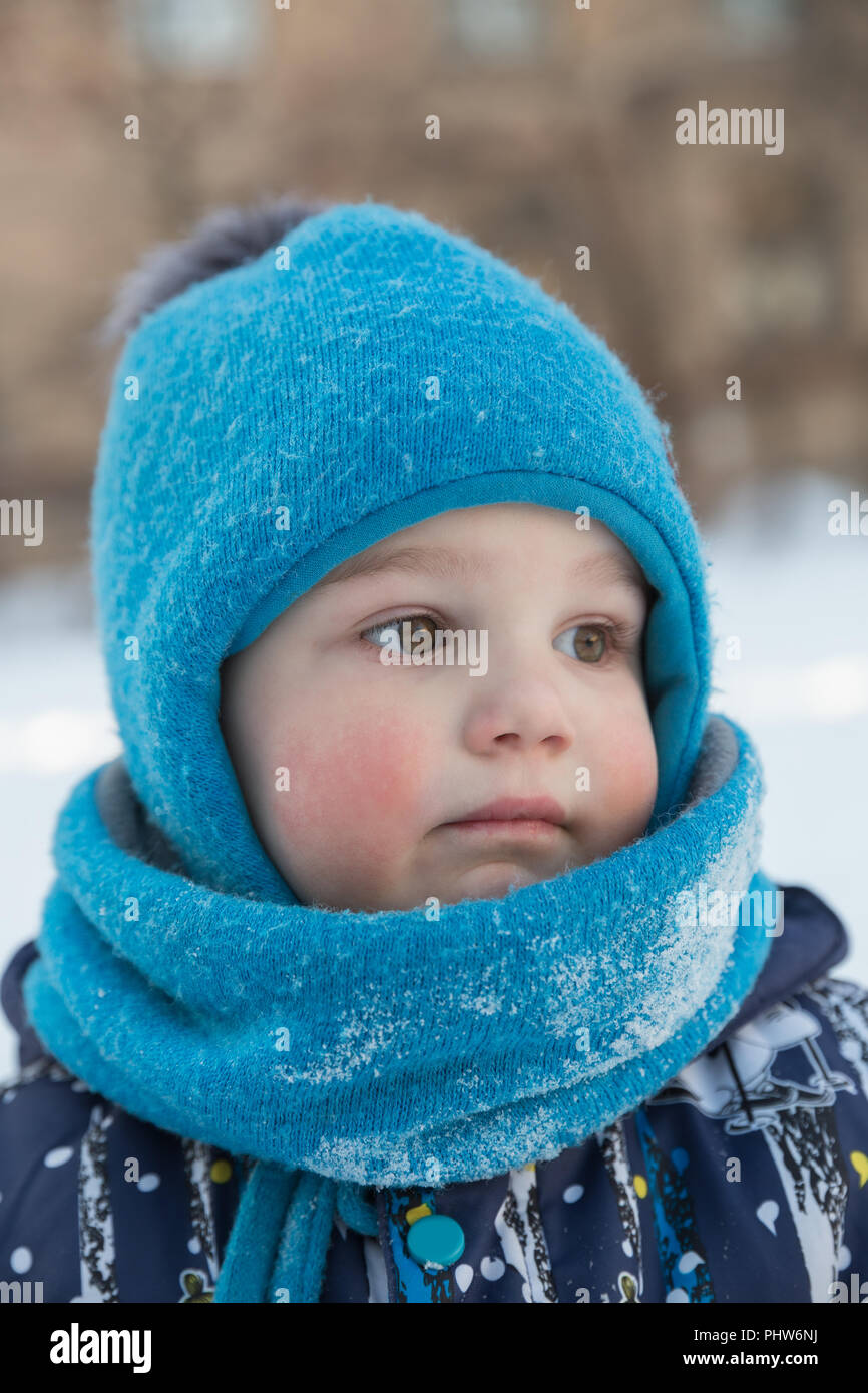 Kind Junge 2-3 Jahre im Winter draußen in blaue Schirmmütze mit pompon und Schal - snood. Close-up Portrait Stockfoto