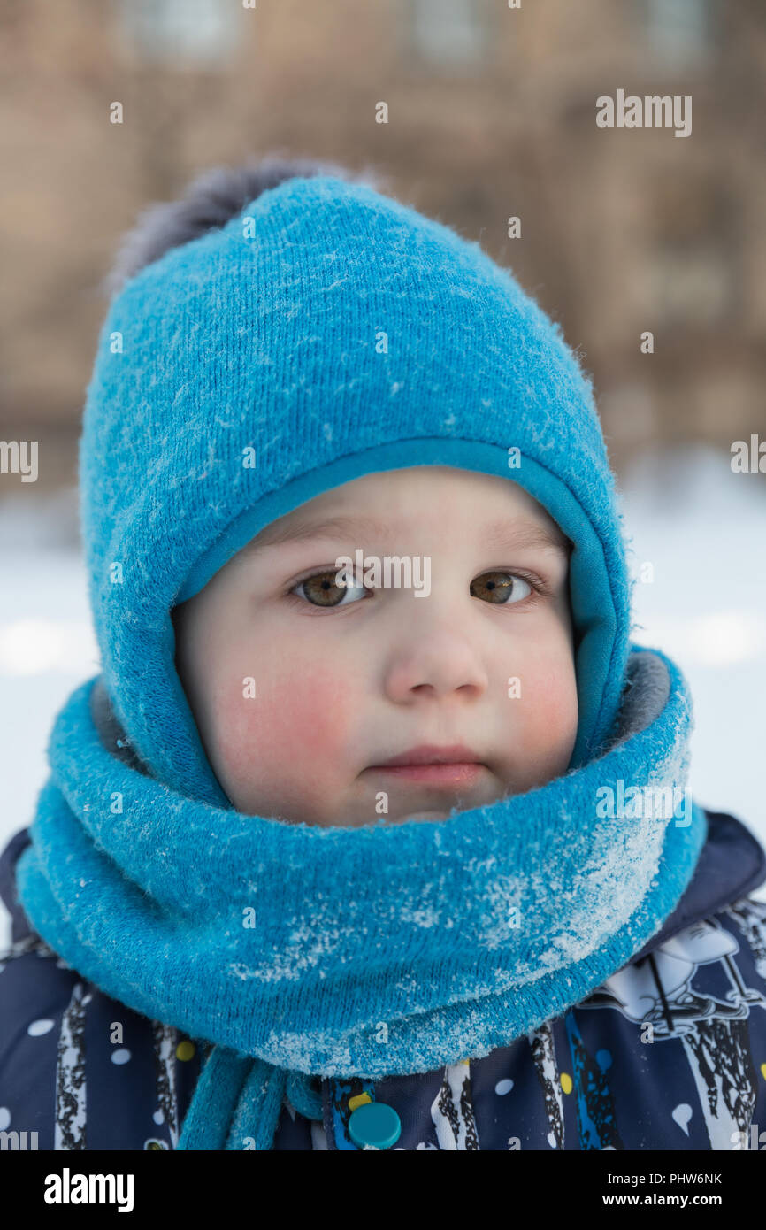 Kind Junge 2-3 Jahre im Winter draußen in Blau gestrickte Wollmütze mit pompon und Schal - snood. Close-up Portrait, an Kamera suchen Stockfoto