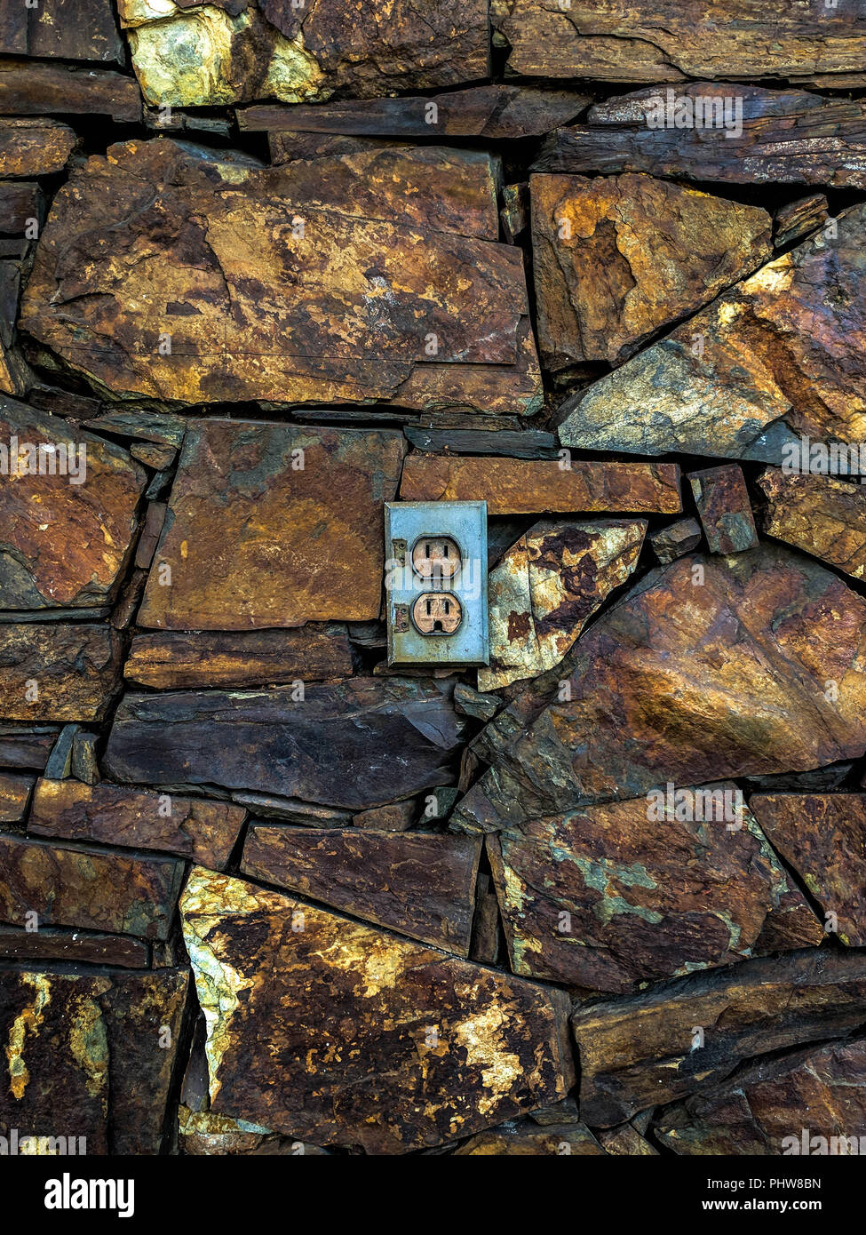 Eine Steckdose (Buchse) in einer verwitterten Eisenstein Mauerwerk. Stockfoto