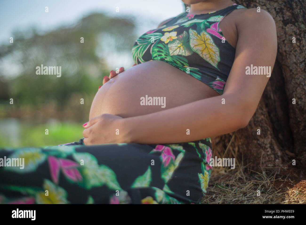 Schwangere Frau in einem Park die Sahne auf den Bauch Dehnungsstreifen zu vermeiden. Stockfoto