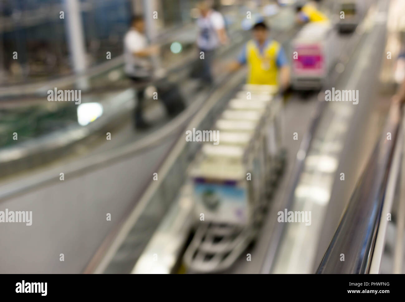 Arbeiter mit Gepäckwagen auf fahrtreppe Flughafen in Bewegungsunschärfe Stockfoto