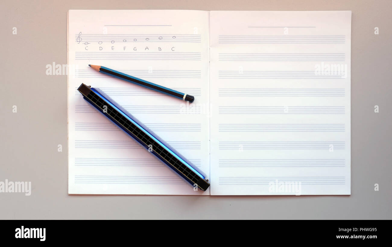 Eine Mundharmonika und einem Bleistift auf eine leere Personal Notizbuch aus Papier Stockfoto