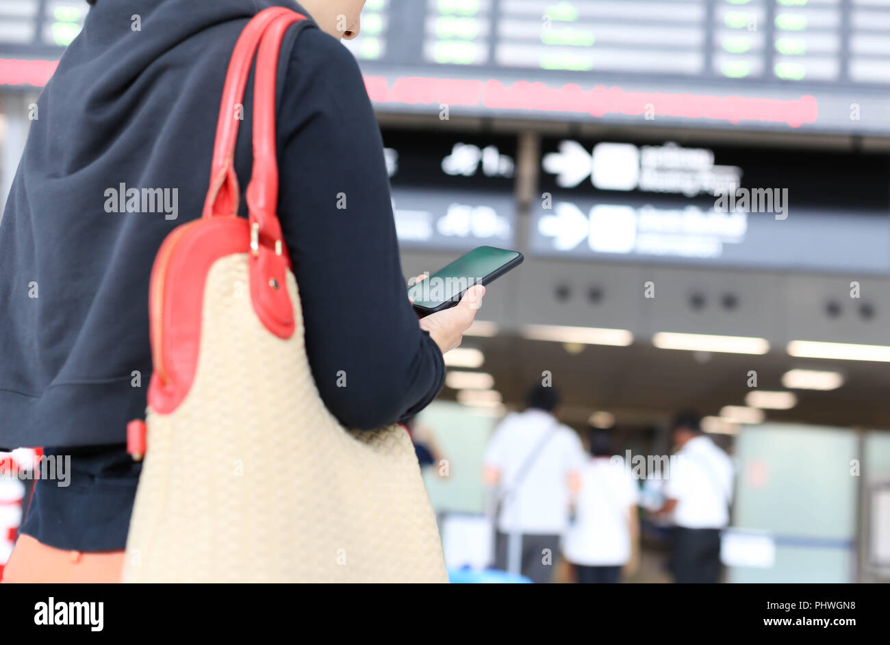 Frau am Telefon und auf Flight Information Board im Flughafen Stockfoto