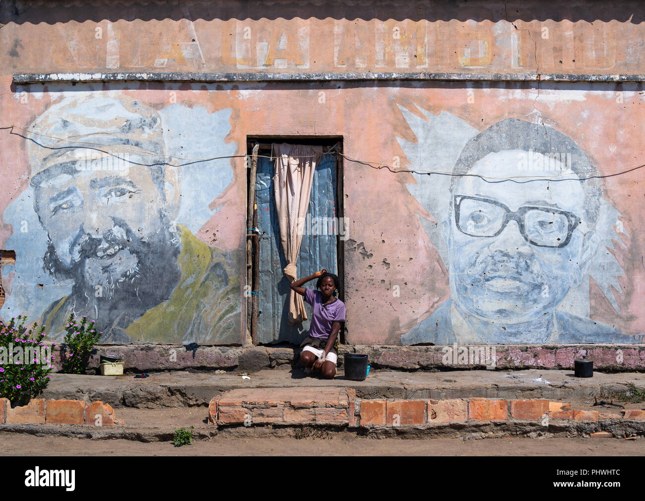 Frau vor einem alten Propaganda Wandmalerei mit Fidel Castro und Jose Eduardo dos Santos, Cunene Provinz, Cahama, Angola Stockfoto