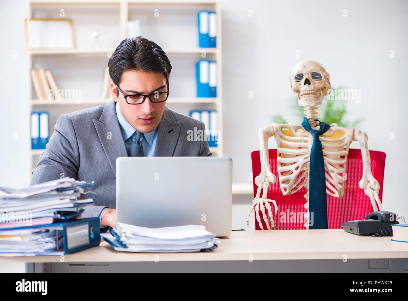 Unternehmer arbeiten mit Skelett im Büro Stockfoto