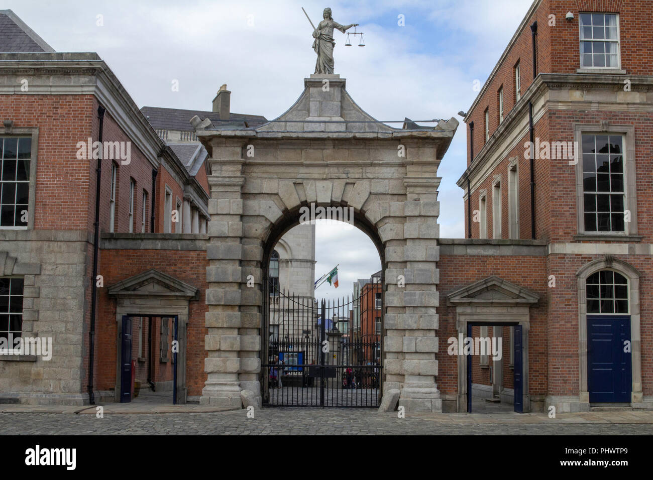 Ein Tor im Schloss von Dublin, Irland mit der Statue der Muttergottes Gerechtigkeit auf der Spitze mit einem Schwert in der einen Hand und die Waage der Gerechtigkeit in der anderen. Stockfoto