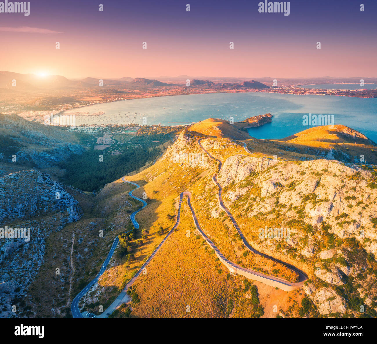 Luftaufnahme der schönen Berge, Straßen, Bäume, blau, lila Himmel, Stadt, Küste, Boote bei Sonnenuntergang auf Mallorca, Spanien. Farbenfrohe Sommer Landschaft mit Stockfoto