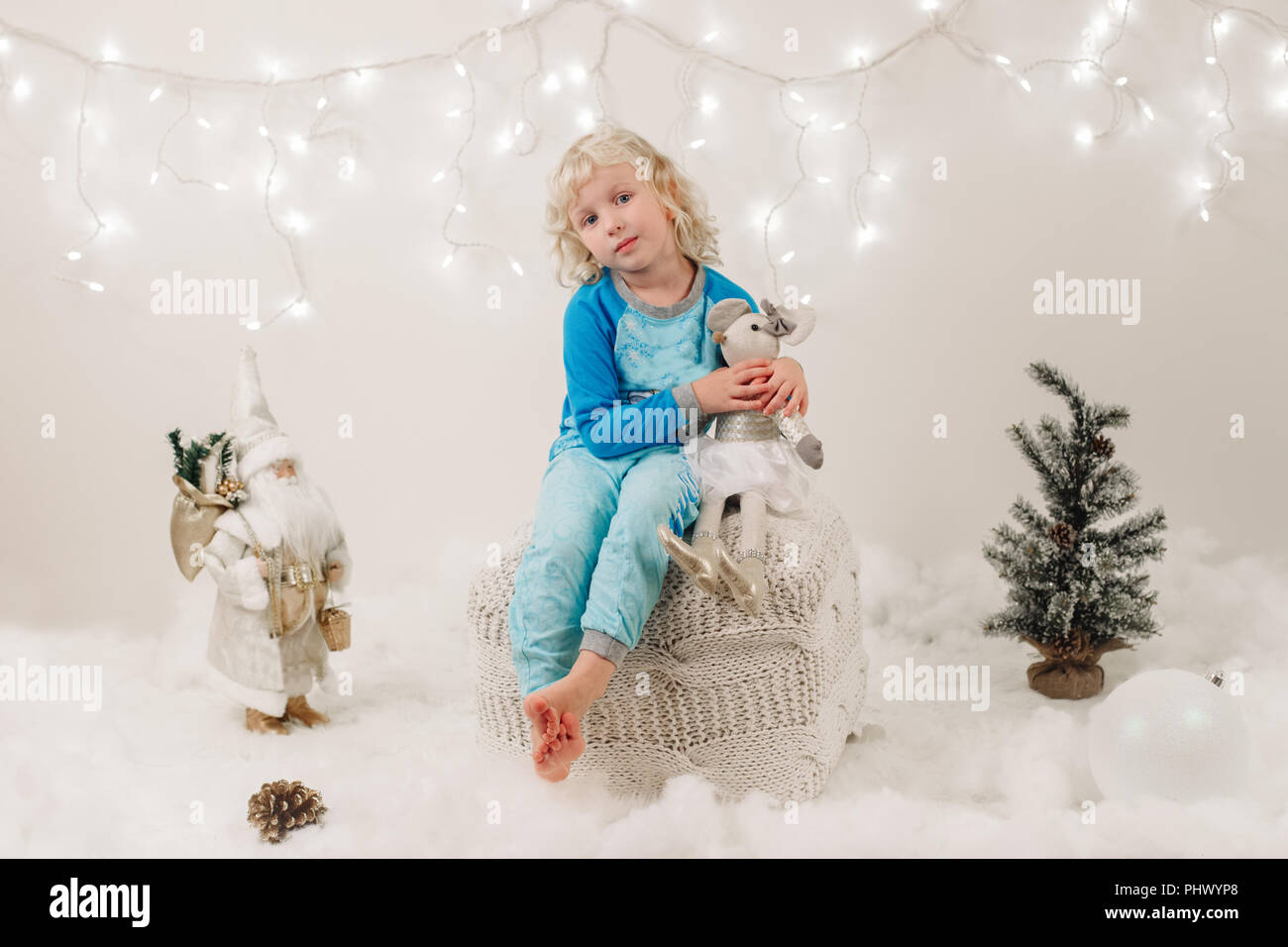 Portrait von blond Kaukasier Kind Mädchen mit blauen Augen sitzen mit Spielzeug Weihnachten oder Neujahr Stockfoto