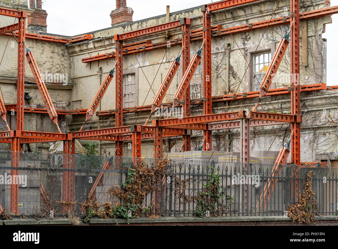 Orange einstellbare buttress unterstützt die alte Mauer auf der Baustelle Stockfoto