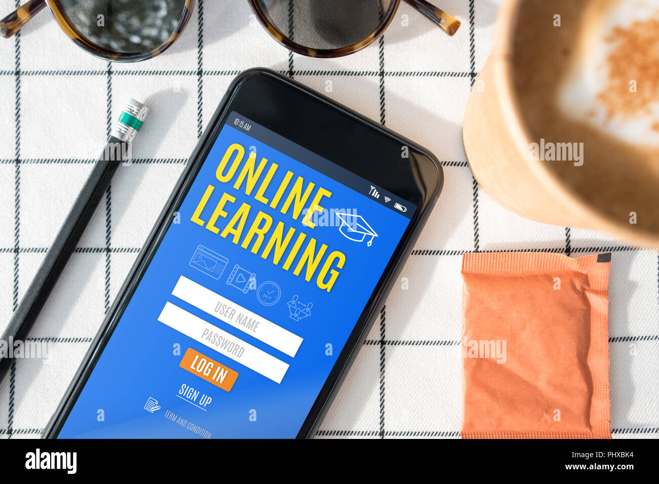 Ansicht von oben online lernen in Funktion auf mobile Bildschirm mit Kaffeetasse, Sonnenbrille, Bleistift auf weiße Tischtuch anmelden. Digitale e Learning Stockfoto