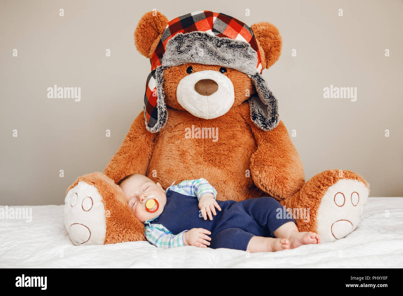 Porträt einer cute adorable White kaukasische Baby neugeborenen Jungen schlafen Träumen mit schnuller Schnuller im Mund, tragen Shirt blau Body, liegend auf dem Bett Stockfoto
